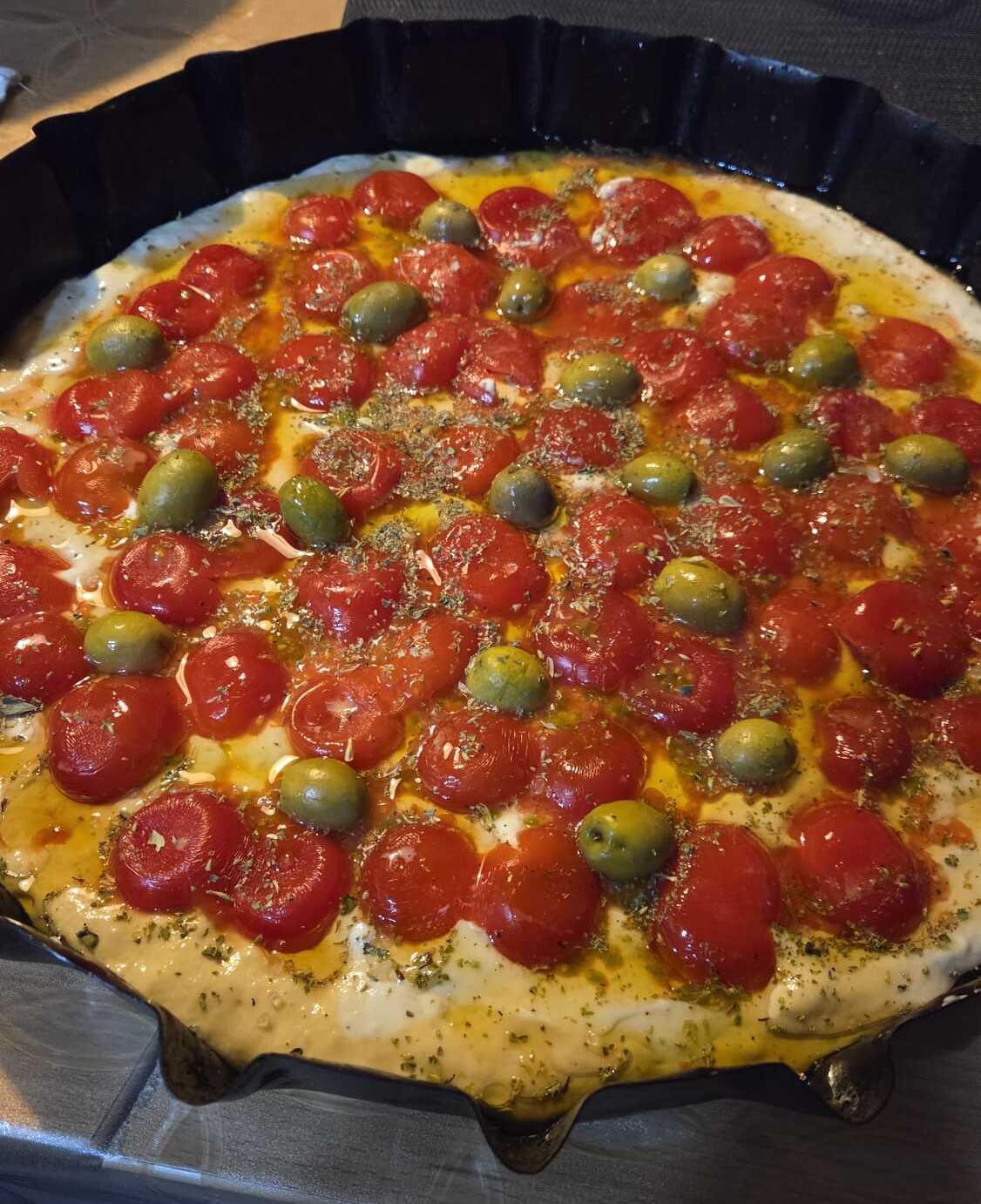 Focaccia barese cruda nella teglia di ferro nera