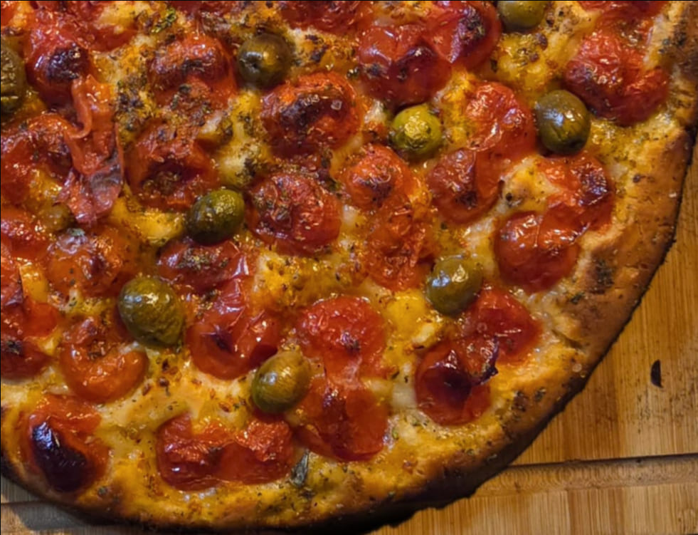 Dettaglio focaccia barese: bordo croccante, pomodorini, olive baresane